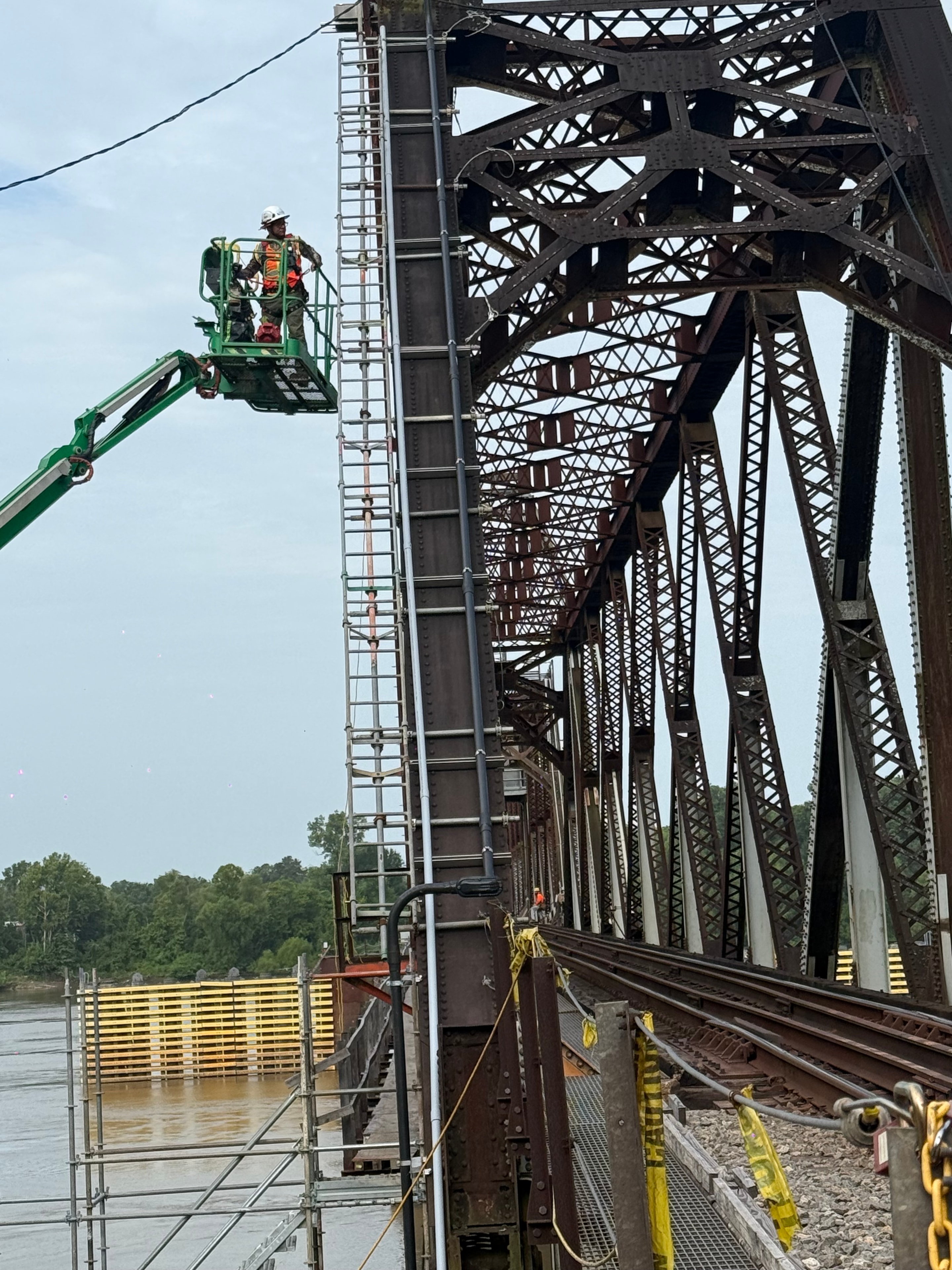 Electrical raceway installation on rotating railroad bridge — worker on boom lift